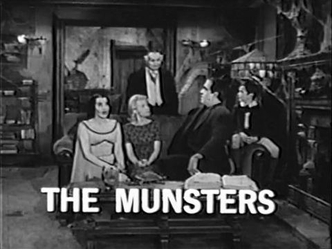 Still from a promo for The Munsters, showing the family seated on a couch.